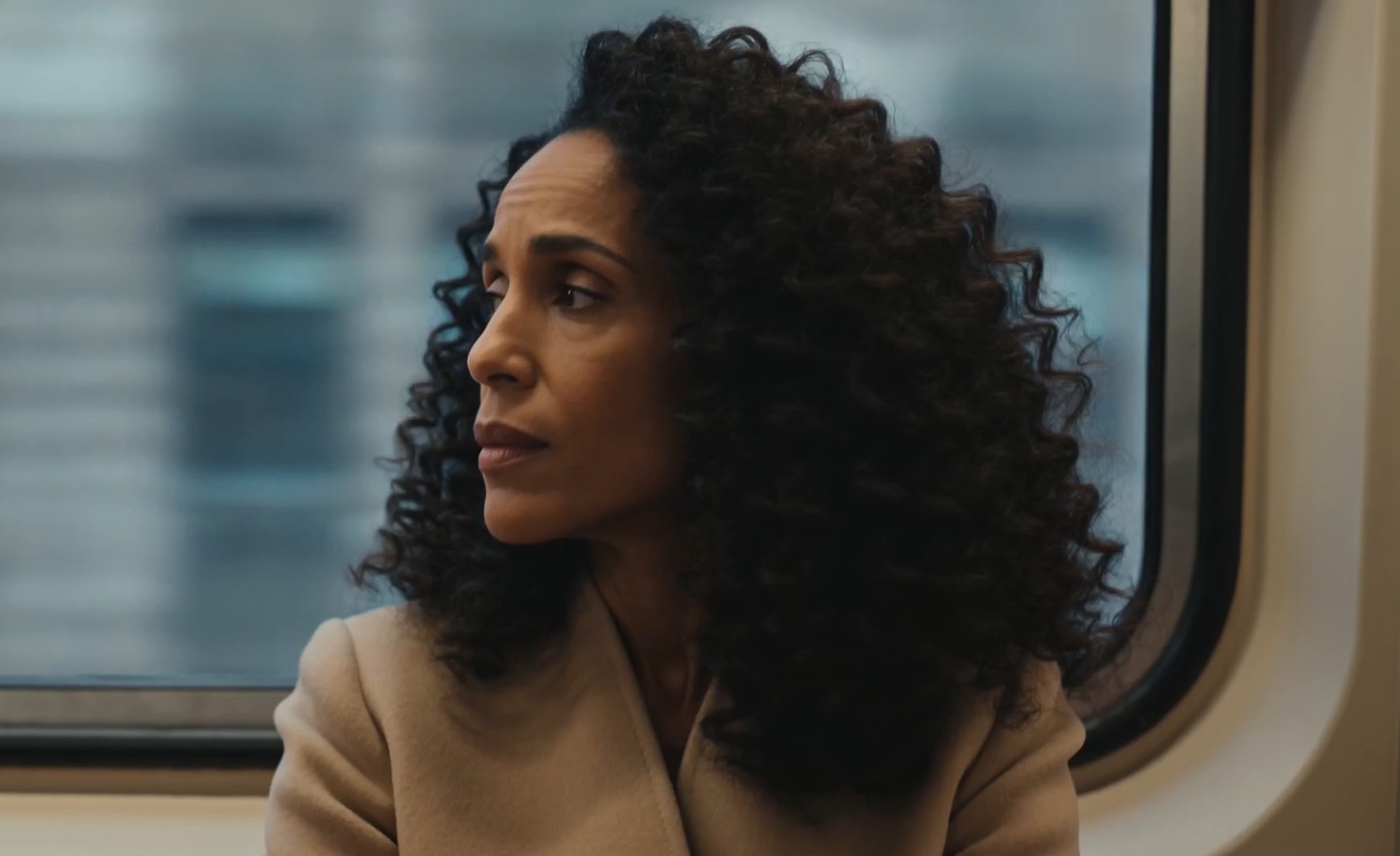 A woman gazing thoughtfully out of a train window
